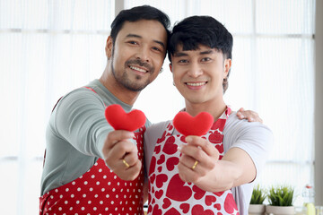 Happy LGBT couple in apron has romantic moment together on Valentine Day at kitchen. Asian gay...