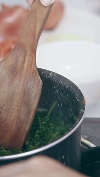 Vertical. A pot of boiling water blanching fiddlehead ferns (Diplazium esculentum) for making pako salad, a local Filipino delicacy showing the authentic daily home life and culinary heritage