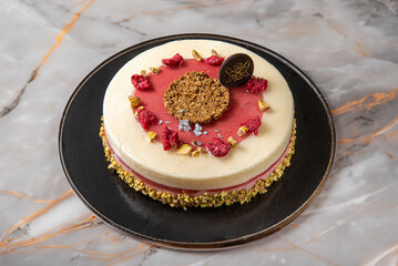 Lemon and red fruit raspberry and strawberry pastry cake ,decorated with hazelnut crumbs isolated in the center on a marble background