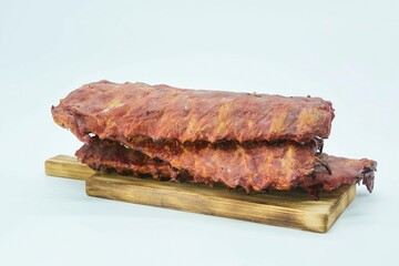Meat dish smoked ribs on a wooden board. The product is ready to use. White background.