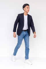 A stylishly dressed man confidently stands indoors, wearing a tailored dress shirt and denim jeans,...
