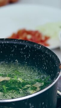 Vertical. Ambient motion of edible fiddlehead ferns or Diplazium esculentum blanching in boiling water to make pako salad, local Filipino delicacy showing the authentic daily home life and heritage