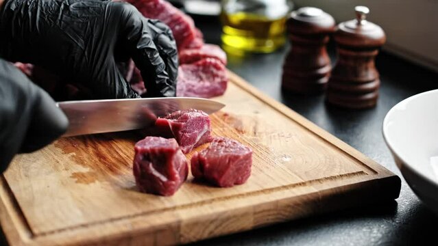 Slicing raw meat on a wooden cutting board in the kitchen. Raw beef meat, cooking process, stock video footage 4k.