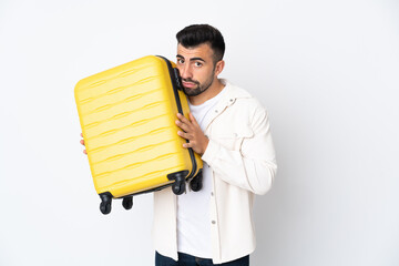Caucasian man over isolated white background in vacation with travel suitcase and unhappy