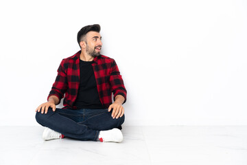 Young handsome man sitting on the floor laughing in lateral position