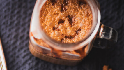 Ice cold coffee with chocolate in a glass jar on a dark background