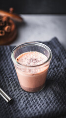 Hot chocolate with cinnamon in a glass on a black background.