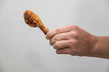 Caucasian man holds a crispy cooked a chicken leg