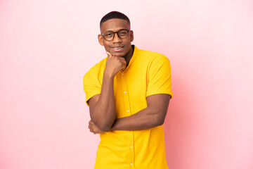 Young latin man isolated on pink background with glasses and smiling