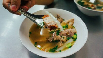 Thai peppery soup and crispy pork, called Kuay Jab clear soup. Noodle roll soup, like a traditional...
