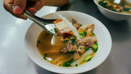 Thai peppery soup and crispy pork, called Kuay Jab clear soup. Noodle roll soup, like a traditional Thai style breakfast but come from China.