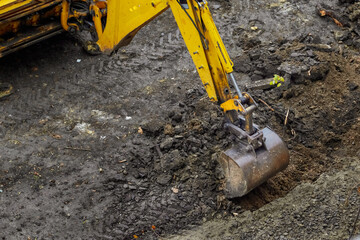 Excavator bucket starts to dig the ground, beginning of construction, earthworks at the...