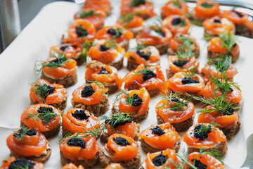 Canapes with salmon and caviar on a white tablecloth.