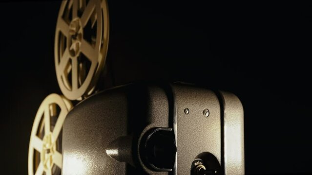 Retro projector playing motion picture in dark room. Timeless flicker old films
