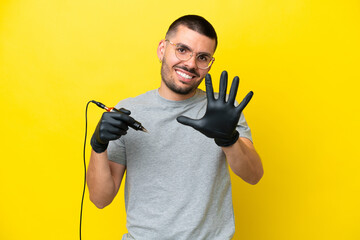 Tattoo artist caucasian man isolated on yellow background counting five with fingers