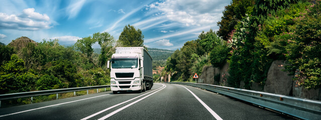 White Truck Or Tractor Unit, Prime Mover, Traction Unit In Motion On Road, Freeway. Asphalt Motorway Highway Against Background Of Hill Landscape. Business Transportation And Trucking Industry © Great Brut Here
