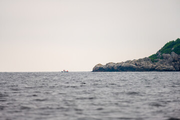 Small boat fishing by large cliffs.