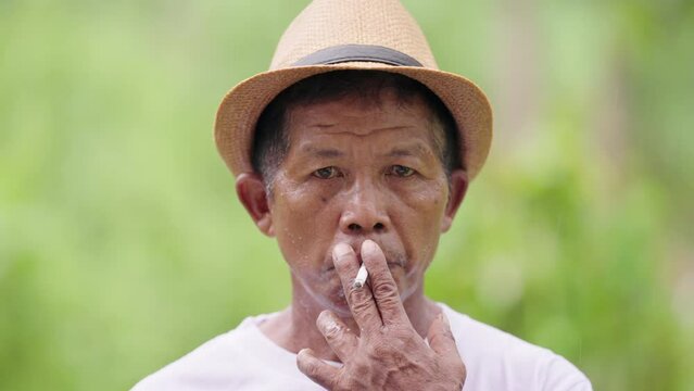 authentic portrait of asian farmer smoking cigarette with slow mo smoke, asia
