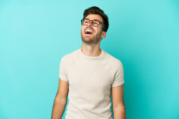 Young caucasian handsome man isolated on blue background laughing