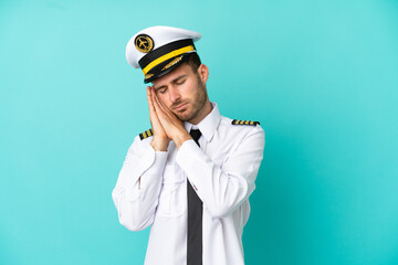 Airplane caucasian pilot isolated on blue background making sleep gesture in dorable expression