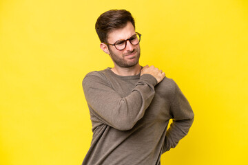 Obraz premium Young caucasian man isolated on yellow background suffering from pain in shoulder for having made an effort