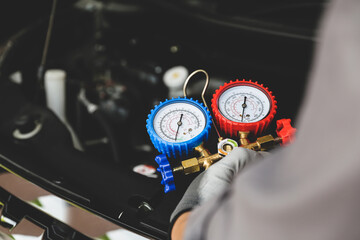 Car mechanic uses air refrigerant meter manifold gauge to check car air conditioner system heat...