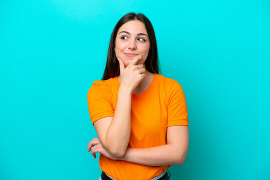 Young caucasian woman isolated on blue background thinking an idea while looking up