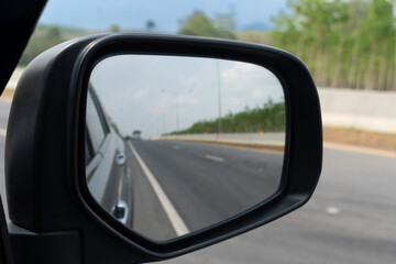 Mirror view of car travel on the asphalt road. Background on front with speed of asphalt road and instead of a roadside barrier and rubber trees.