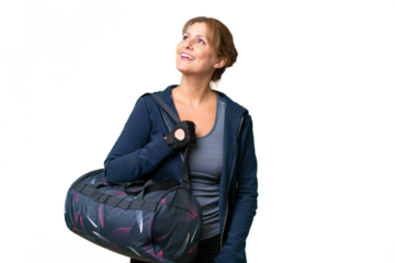 Middle-aged sport woman with sport bag over isolated background happy and smiling