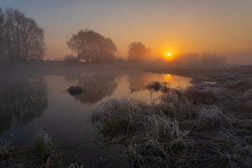 Obraz premium rising sun over the foggy morning.reflection sun in the water