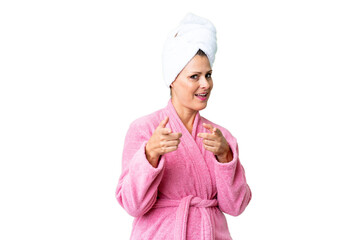 Middle age caucasian woman in a bathrobe over isolated background pointing to the front and smiling