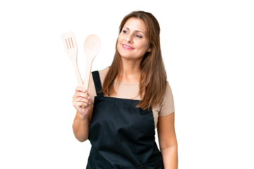 Middle age caucasian woman holding a rolling pin over isolated background looking to the side and smiling