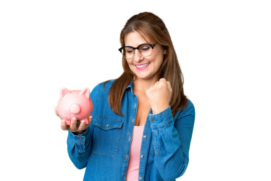 Middle age caucasian woman holding a piggybank over isolated background celebrating a victory
