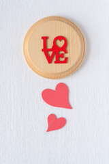 laser-cut crafting embellishments with the word love on a wooden roundel and hearts arranged on crepe paper