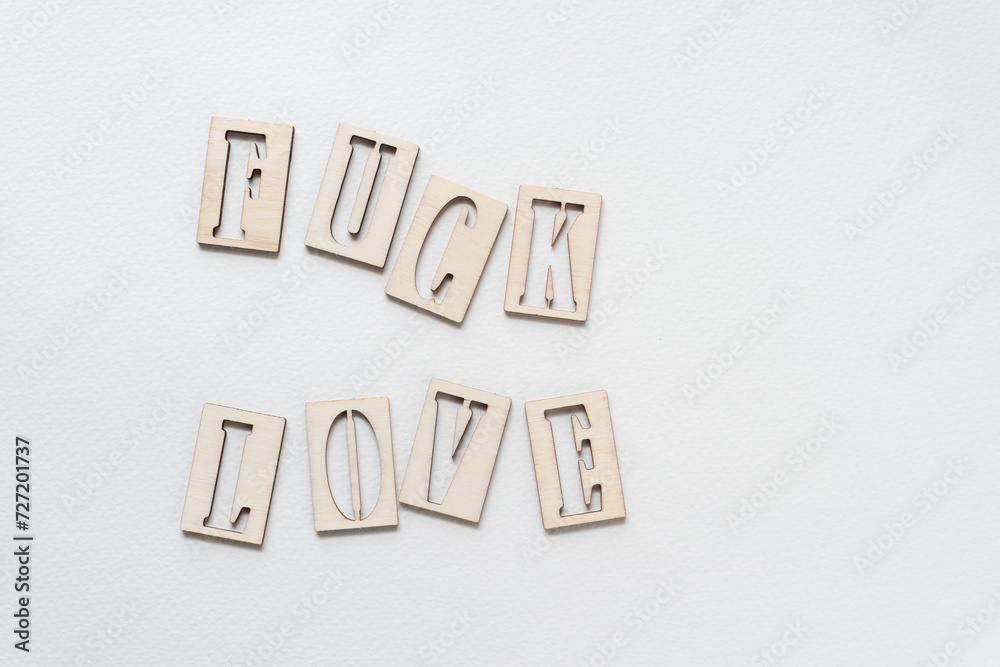 Sticker fuck love composed of wooden letters with stencil font on blank paper