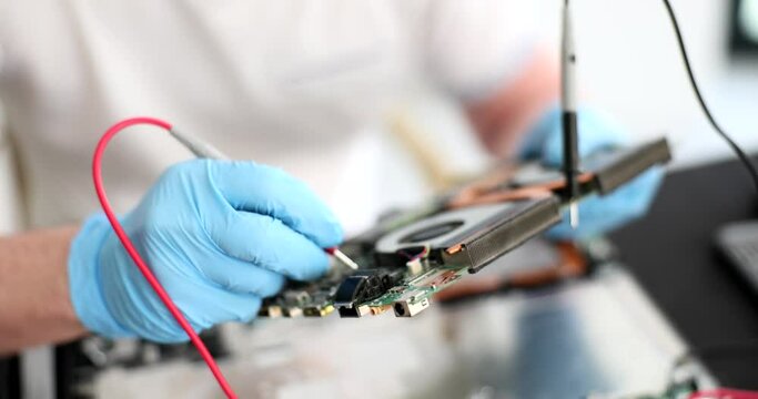 Computer engineer with tester inspects motherboard. Repair service of computer and printing equipment