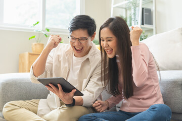 Happy excited, smiling asian young couple love using tablet pc, great deal or business success,...