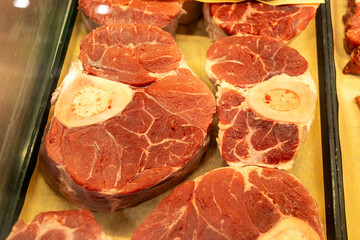 Raw beef steaks - displayed in a row - rich marbling - fresh cut - bone-in - vibrant red color. Taken in Toronto, Canada.