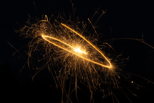 A sparkler illuminates dark evening - bright, golden sparks fly - celebration holiday - new years day, fourth of july, canada day. Taken in Toronto, Canada.