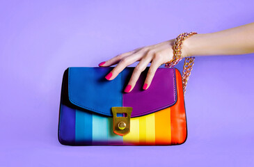 Colourful fashion rainbow purse with beautiful hand. isolated on purple background.  - 727210384
