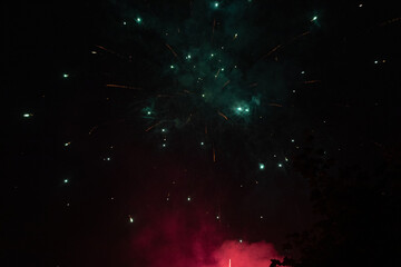 Burst of green and red fireworks at night - vibrant streaks and sparks - smoke clouds -...