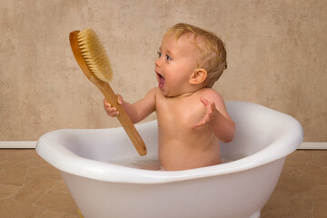 Cute blonde baby boy with bath brush