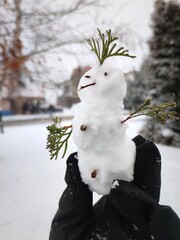A man holds a little figure of snowman in his hand.
