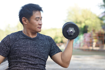 Handsome Asian man exercises outdoor, lift dumbbell. Concept, Exercise for health bodybuilding. Strengthen muscle. Weight lifting. Healthy lifestyle. Sport equipment. Work out makes strong of body.   