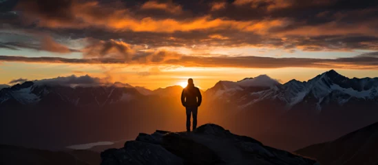 Foto op Aluminium Silhouette of man on cliff enjoying sunset view in mountains during summer.AI Generative © hafsa
