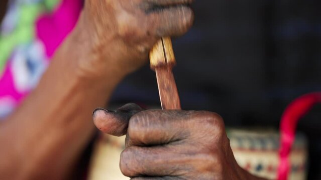 close up of elderly hands chopping areca nut with traditional tool, local identify