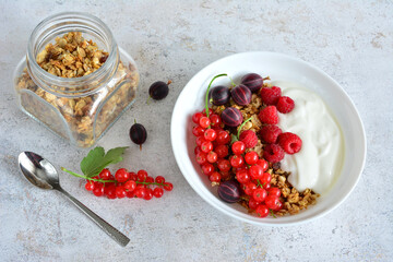 muesli with yoghurt and berries in white bowl top view