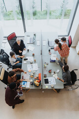 Overhead view of a diverse team engaging in a collaborative effort at a spacious office table, with...