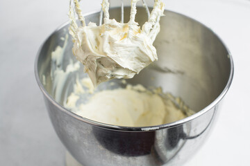 Cream colored american buttercream on a whisk attachment, buttercream on a whisk