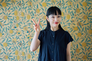 笑顔でピースサインをする若い女性